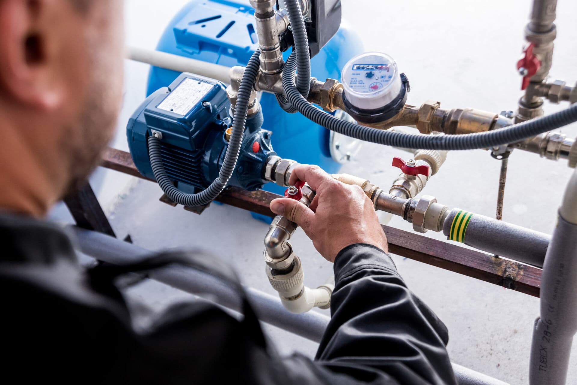 Professional technician servicing water system under kitchen sink