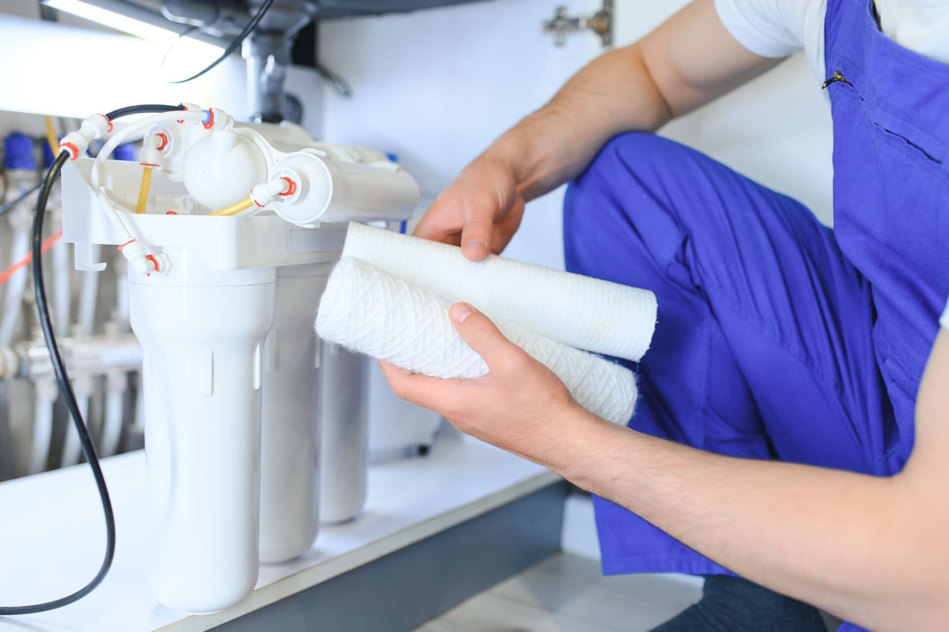 Technician replacing filter cartridges under sink